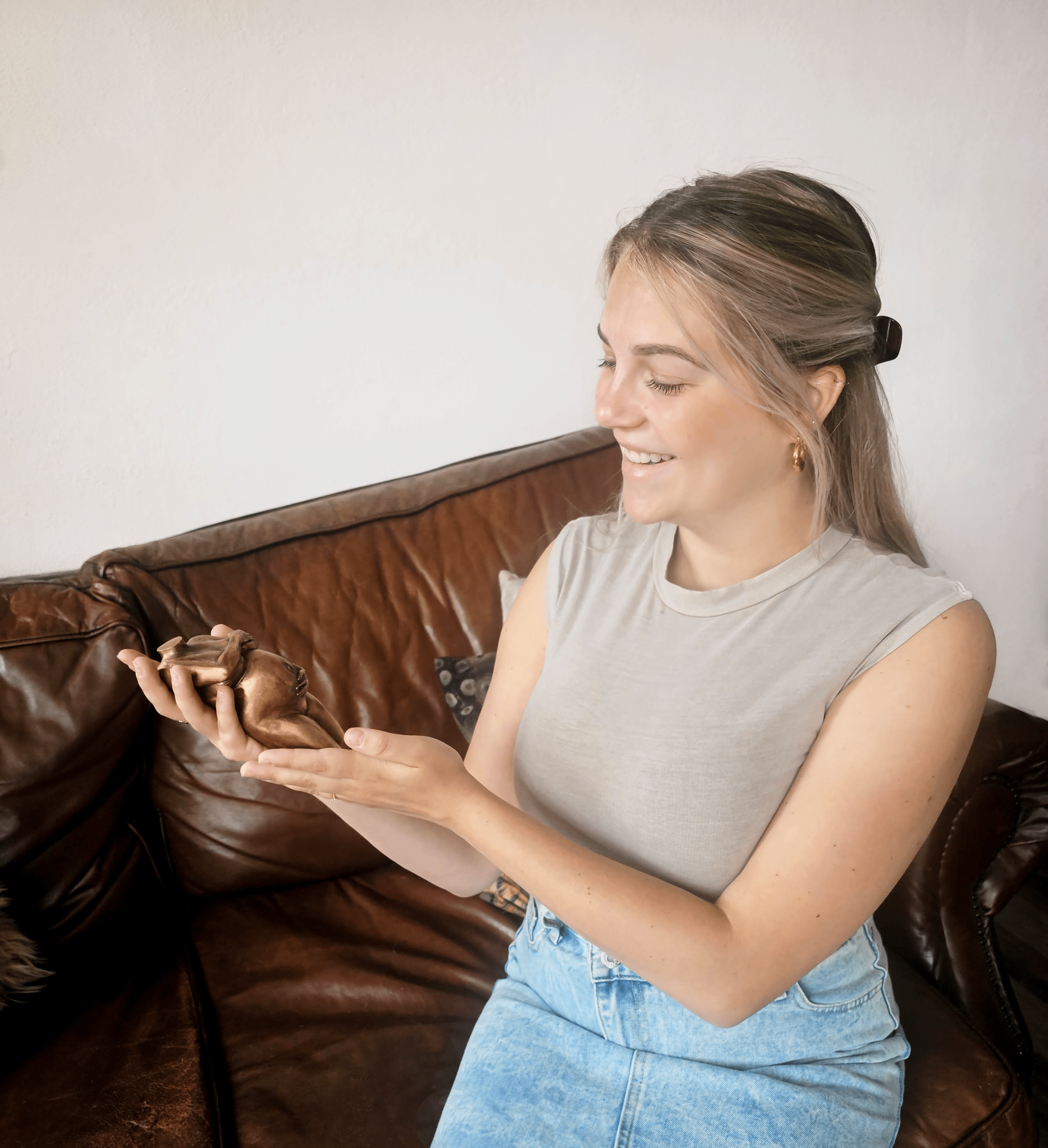 Sally lacht vrolijk naar haar zwangere buikbeeld in brons terwijl ze zit op de bank. cadeau zwangere vrouw